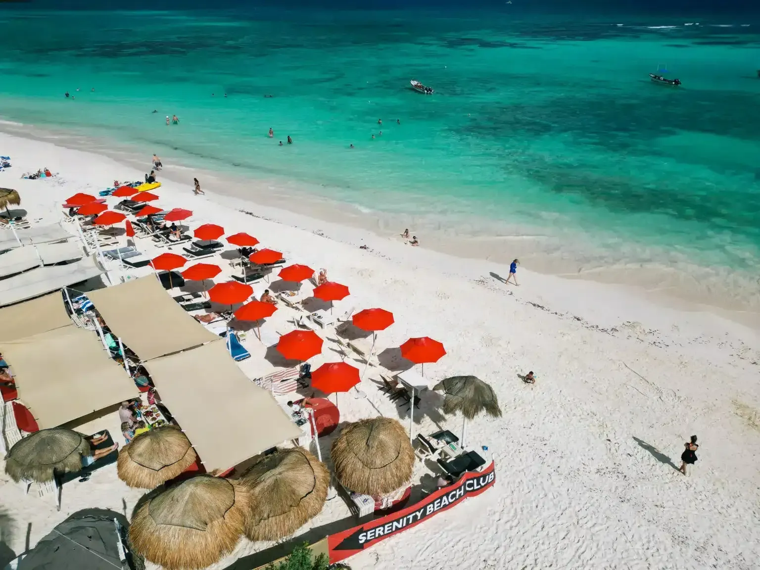 Una vista aérea de una playa con sombrillas rojas.
