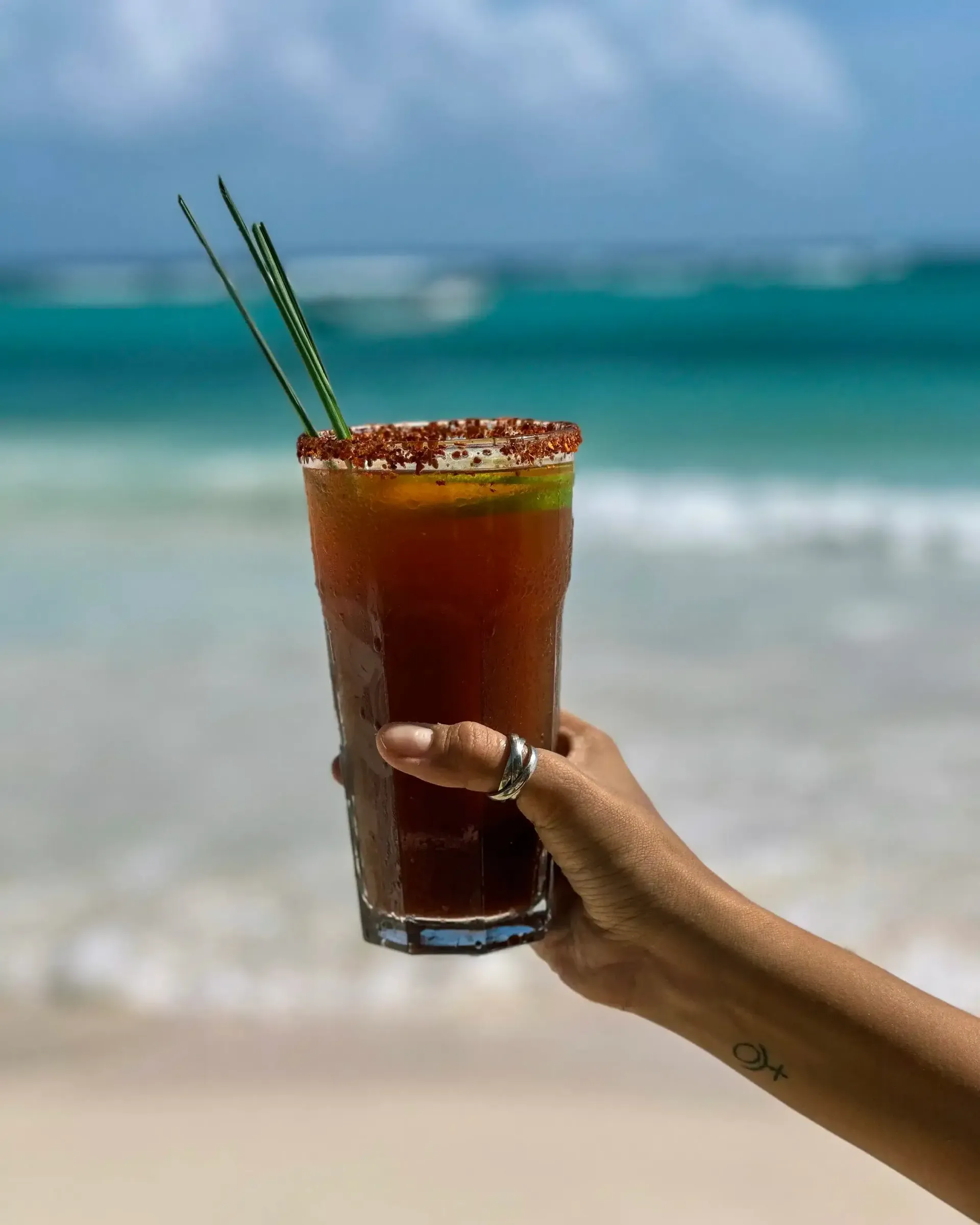 A hand holding a glass in a beach