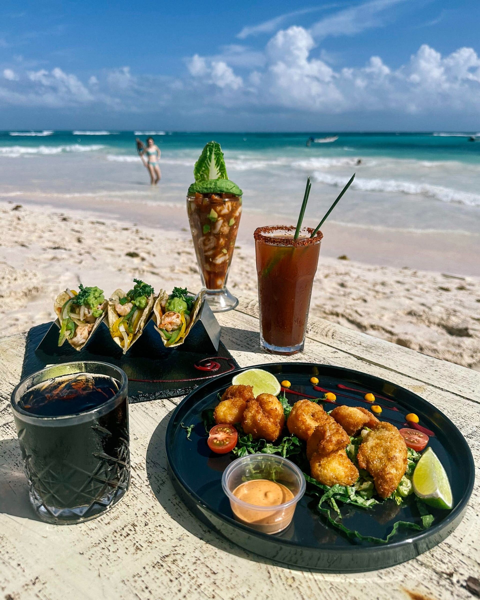Hay un plato de comida y bebidas en la playa.