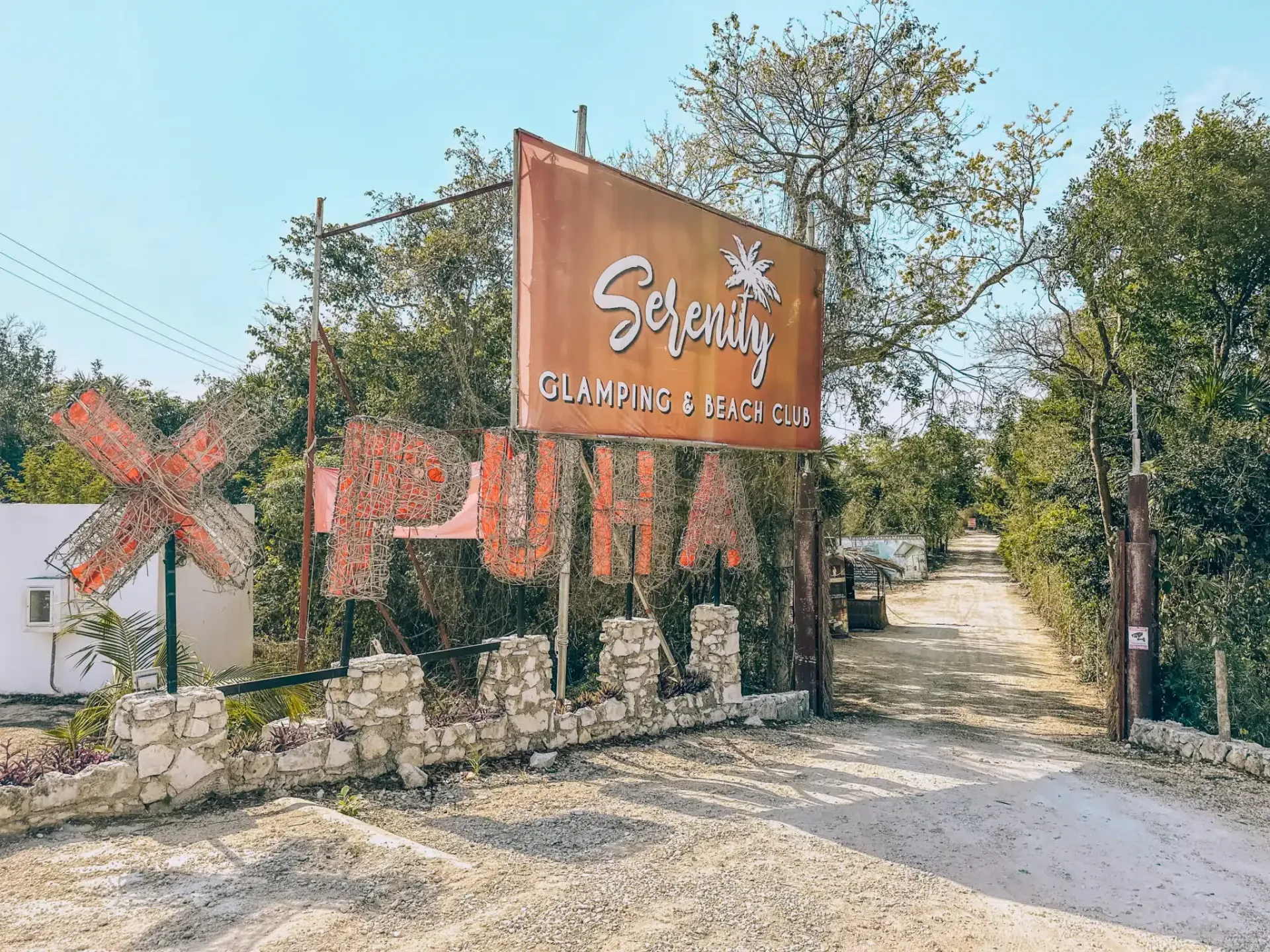 Un gran cartel cuelga sobre un camino de tierra.