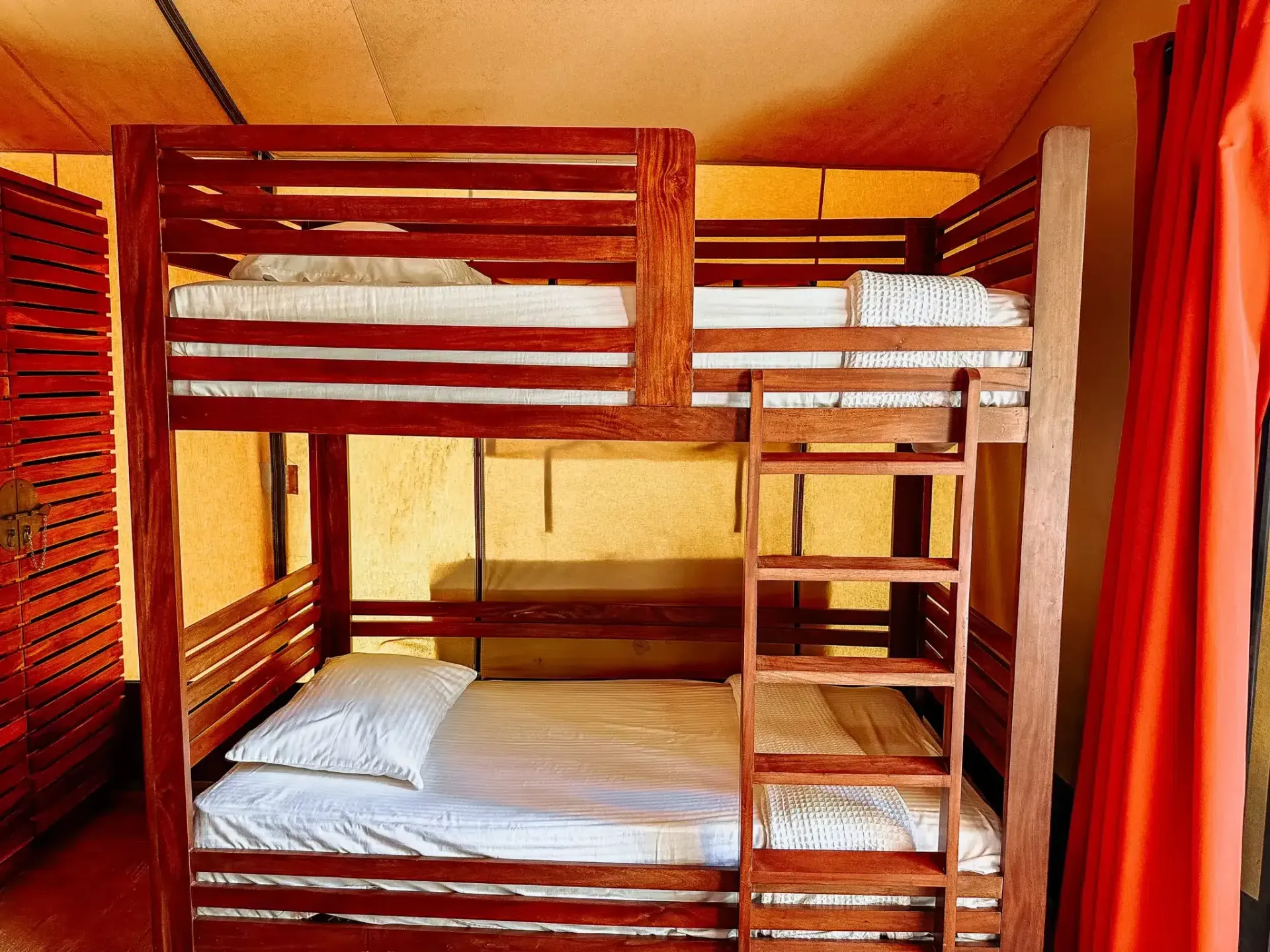 Una litera con escalera en una habitación con cortinas rojas.