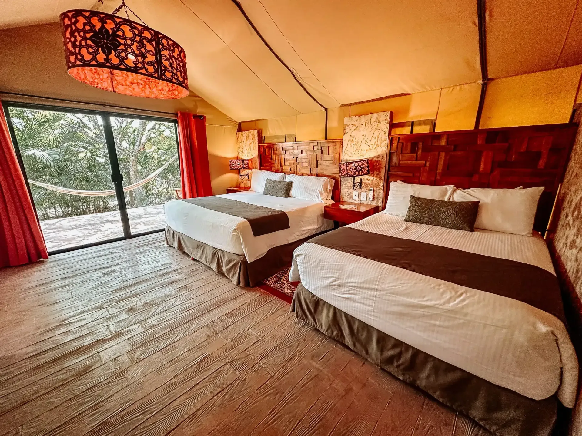 Una habitación de hotel con dos camas y una puerta corrediza de cristal.