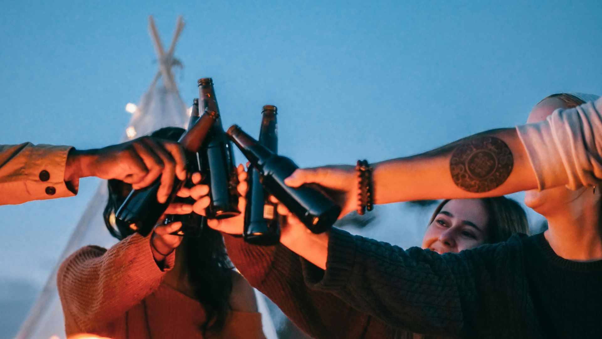 Un grupo de personas está brindando con botellas de cerveza.