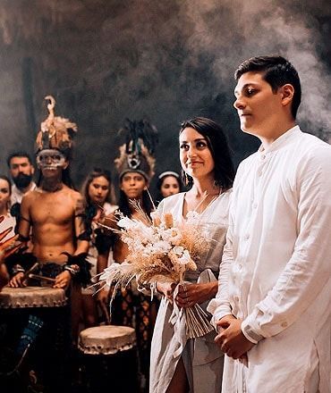 Una novia y un novio están parados uno al lado del otro frente a un grupo de personas.