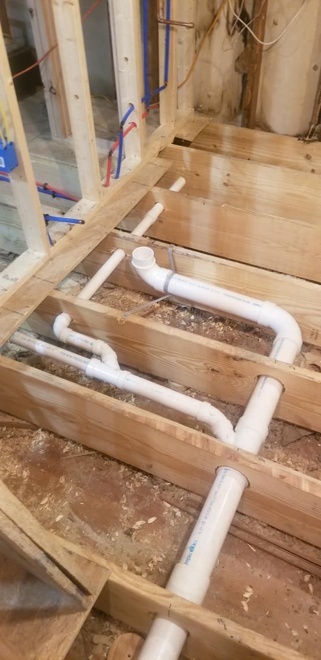 Plumbing pipes installed in a wooden floor frame, with surrounding construction.
