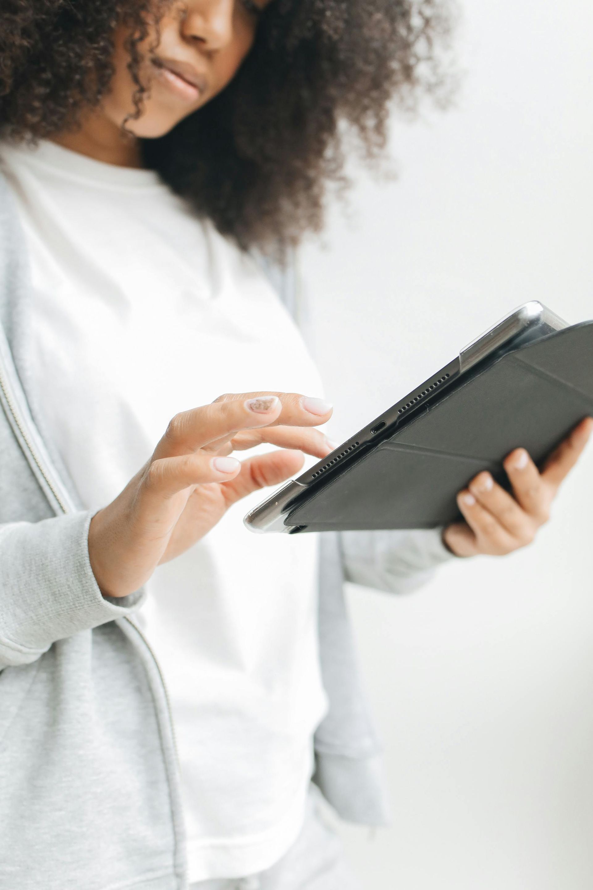 Person using a tablet, hands visible, wearing a gray jacket and white shirt.