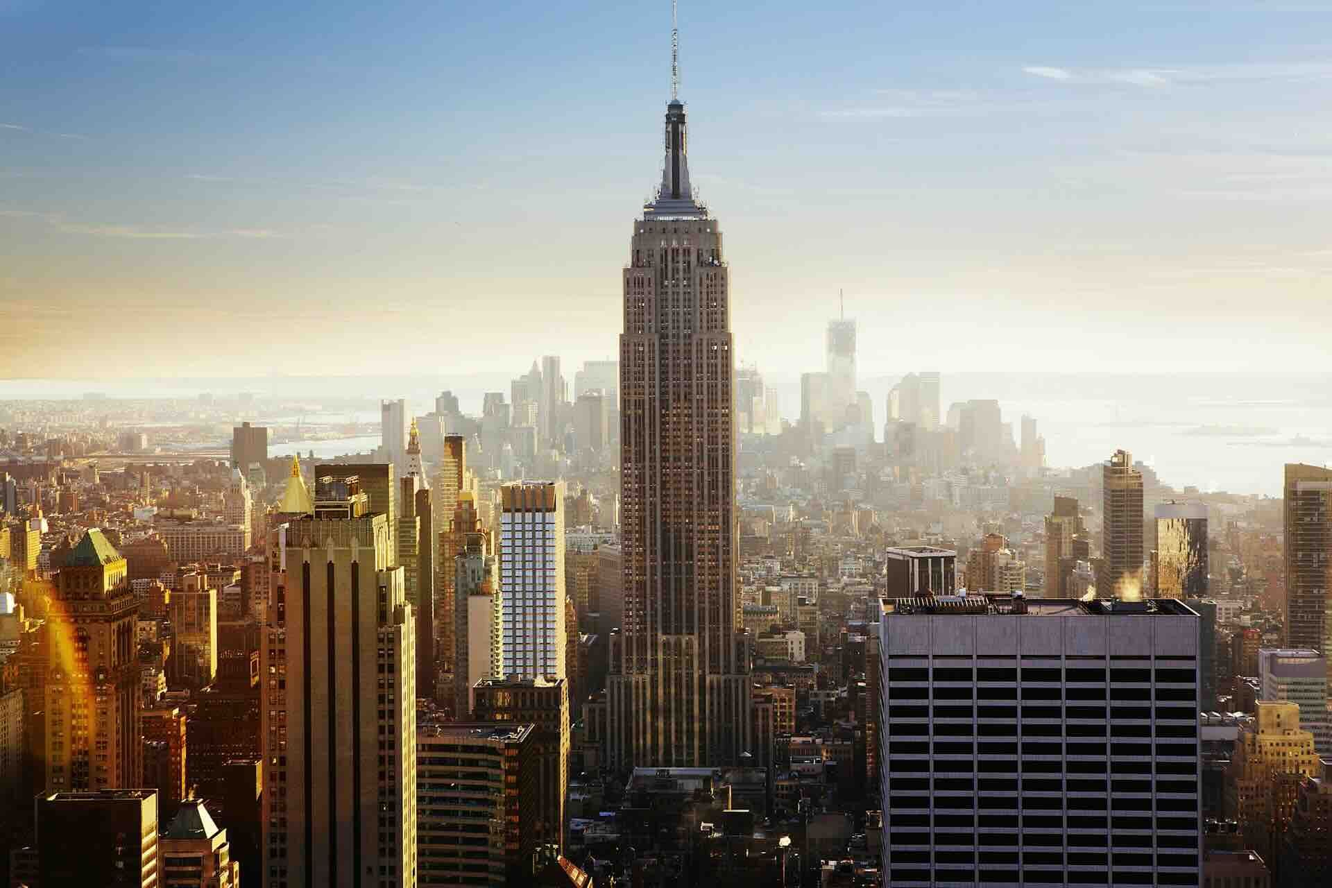 Empire State Building in New York City, tall skyscraper amidst cityscape at sunset.