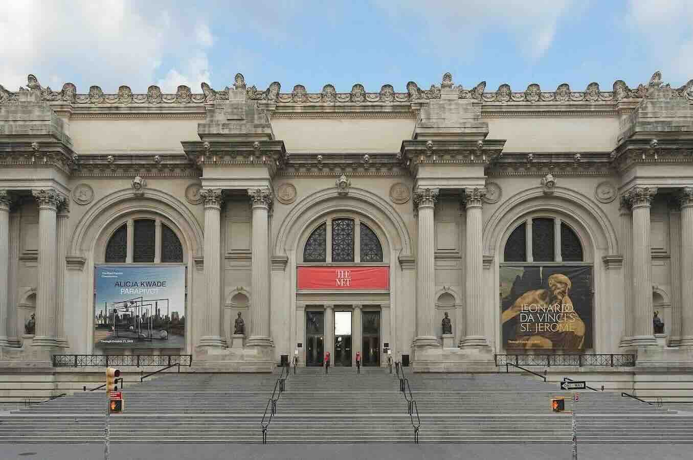 The Metropolitan Museum of Art, New York City. Stone facade with grand entrance, steps, and banners.