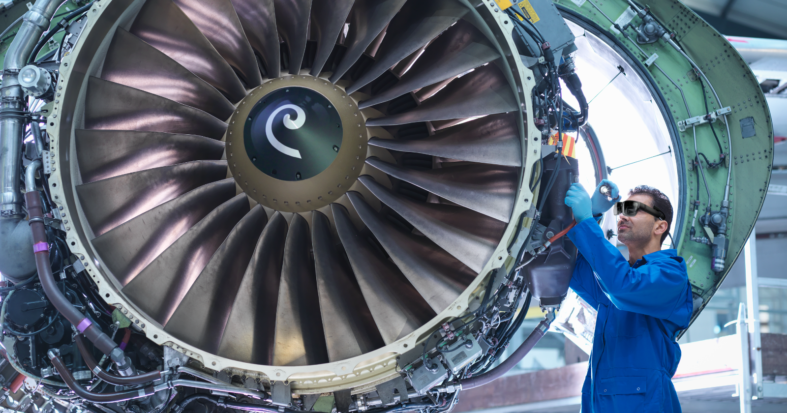 A man is working on an airplane engine in a factory.