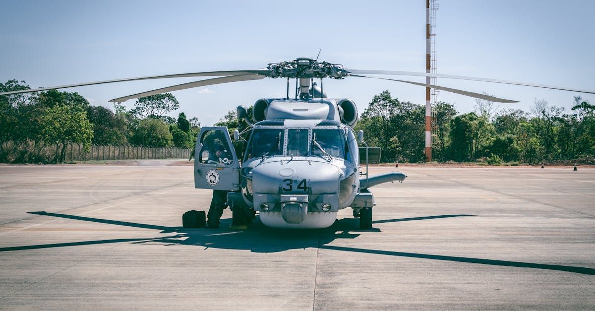 A military helicopter is parked on the tarmac of an airport.