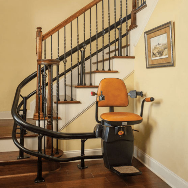 A stair lift with an orange seat is next to a staircase