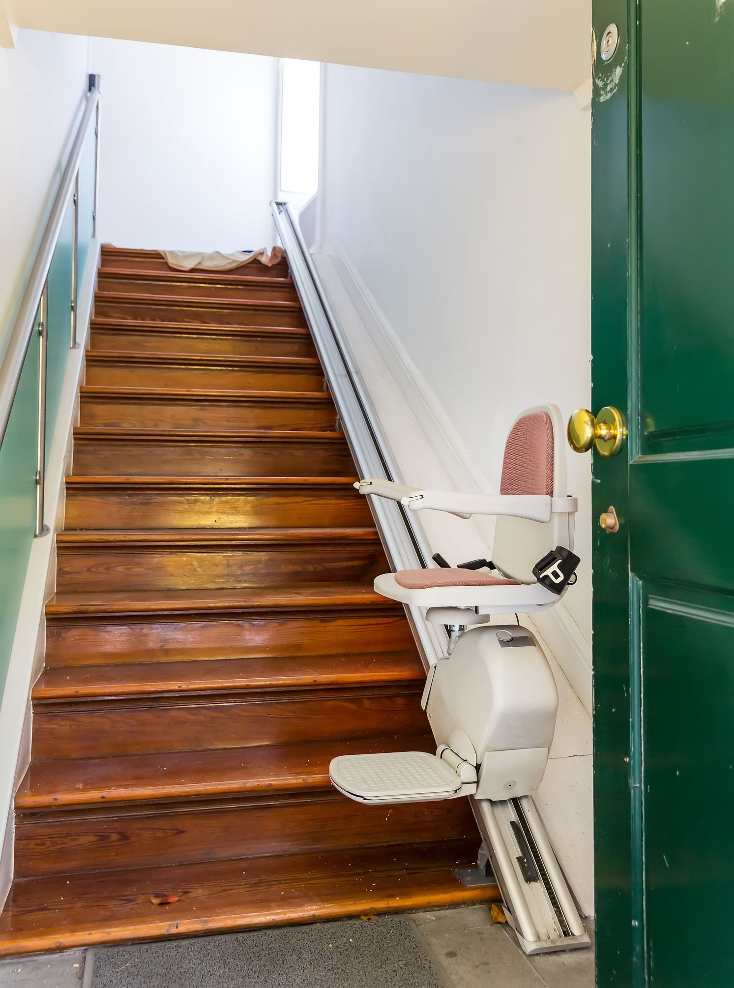 A wooden staircase with a chair on the bottom of the stairs