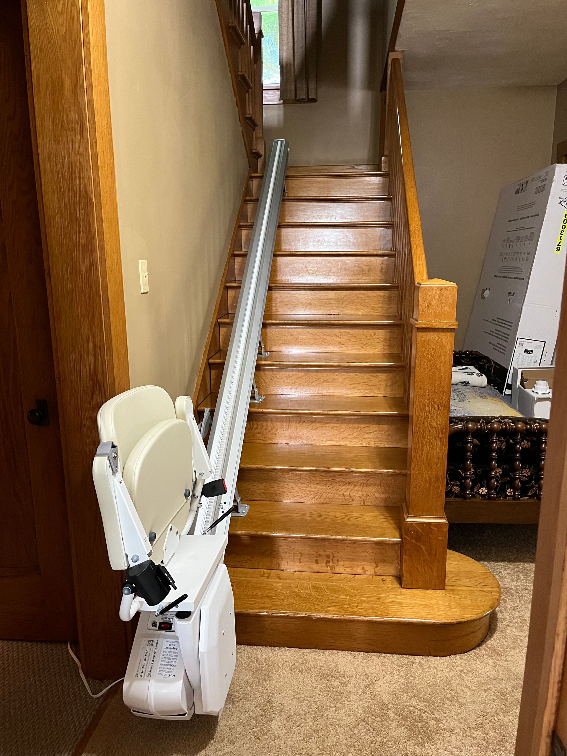 A stair lift is attached to the side of a wooden staircase.