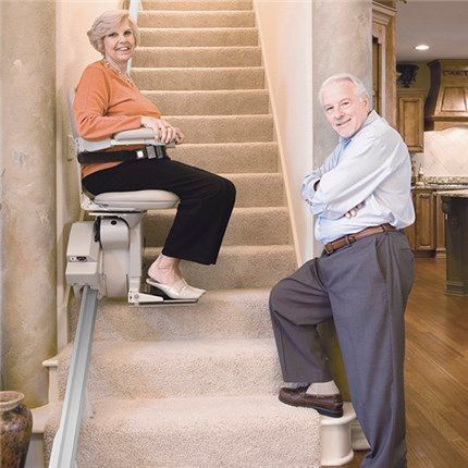 A man and a woman are sitting on a stair lift