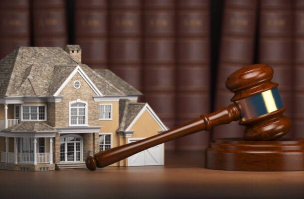 House model and judge's gavel on a desk in front of law books, symbolizing a real estate legal issue.