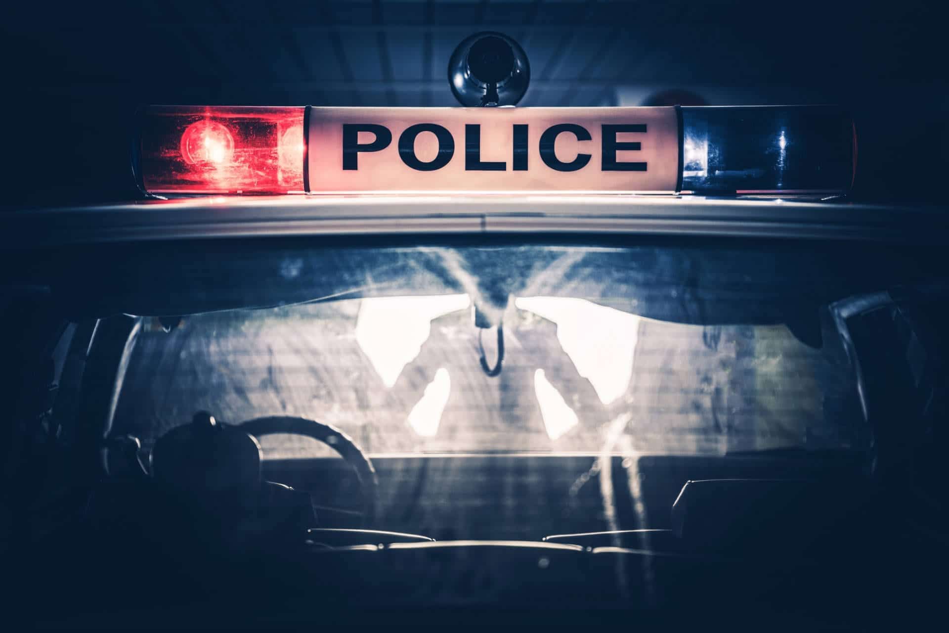 Police car at night, illuminated dashboard, flashing red and blue lights, 