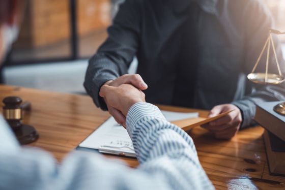 A man is shaking hands with another man at a table.