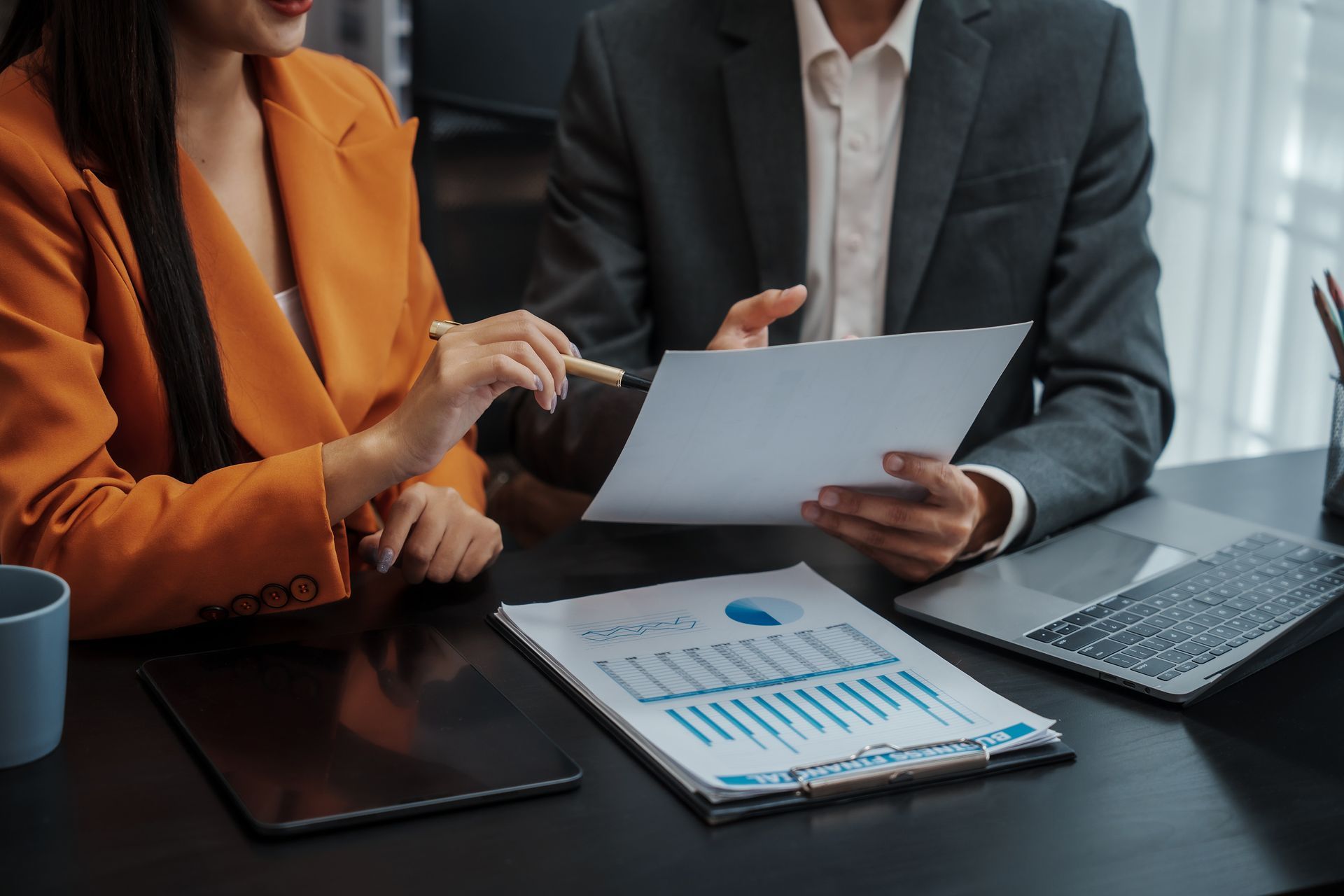 A man and a woman are sitting at a table looking at a piece of paper.