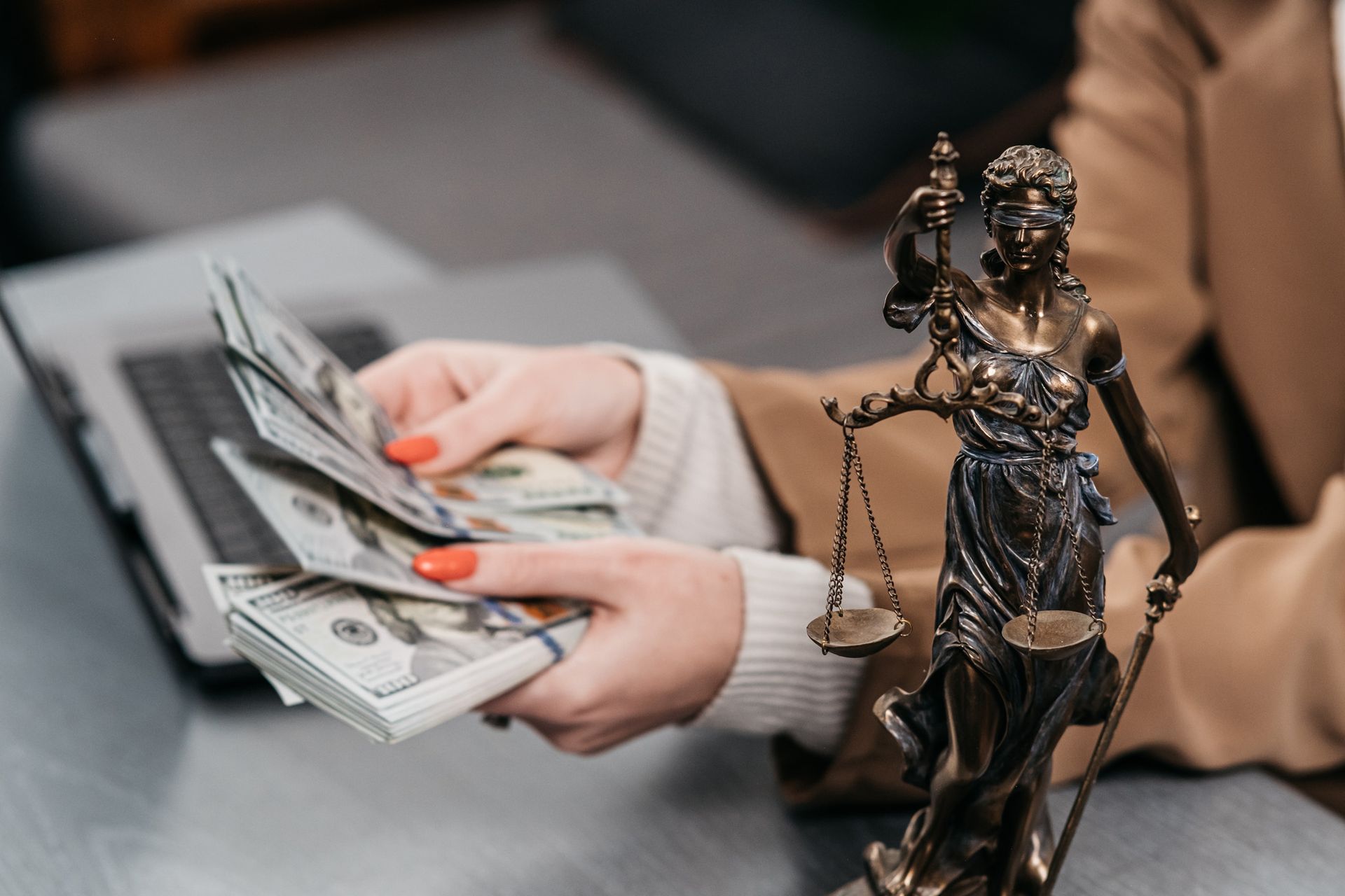 A woman is holding a stack of money in front of a statue of justice.