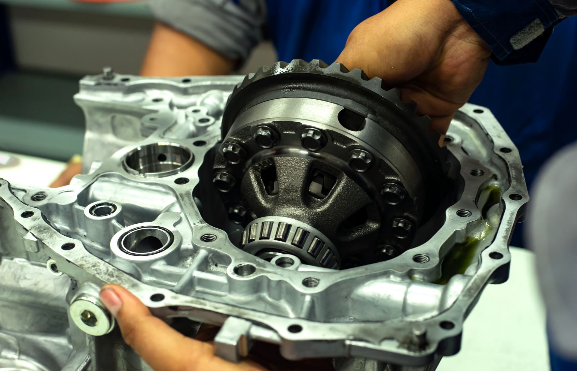 Hands installing differential gear into a metal casing, showing internal mechanical components.