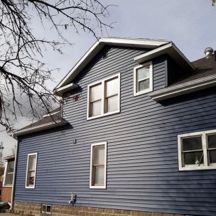 A blue house with white windows and a black roof.