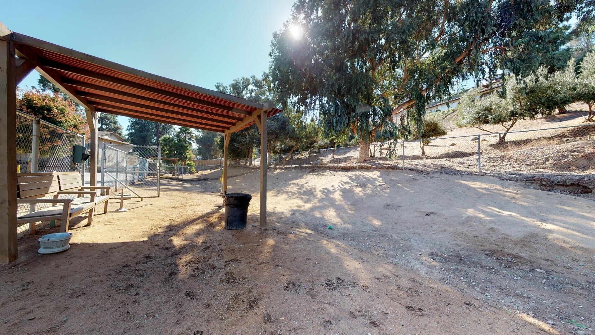 A wooden shelter is sitting in the middle of a dirt field.