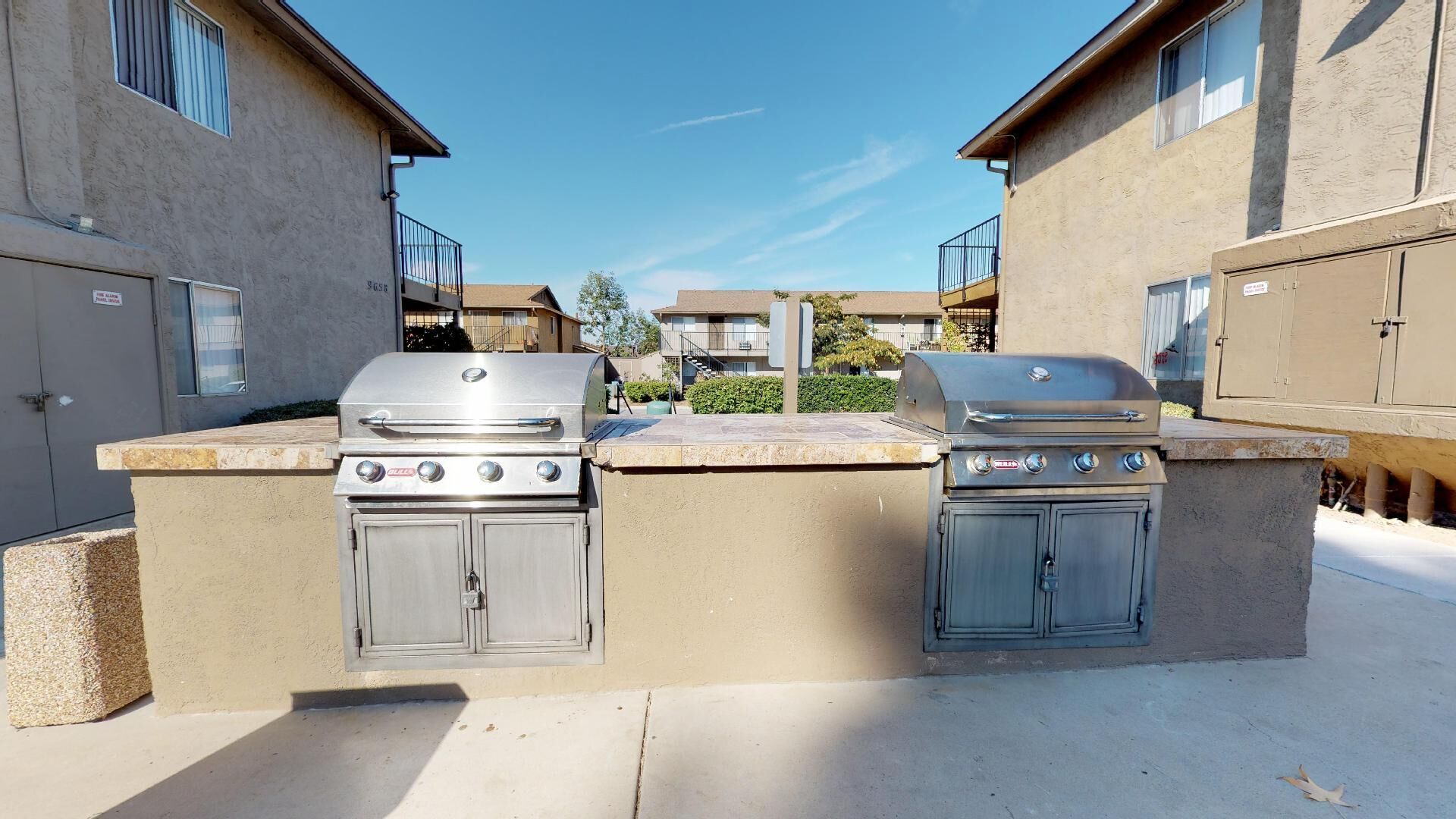 A grill is sitting in the middle of a patio in front of a building.