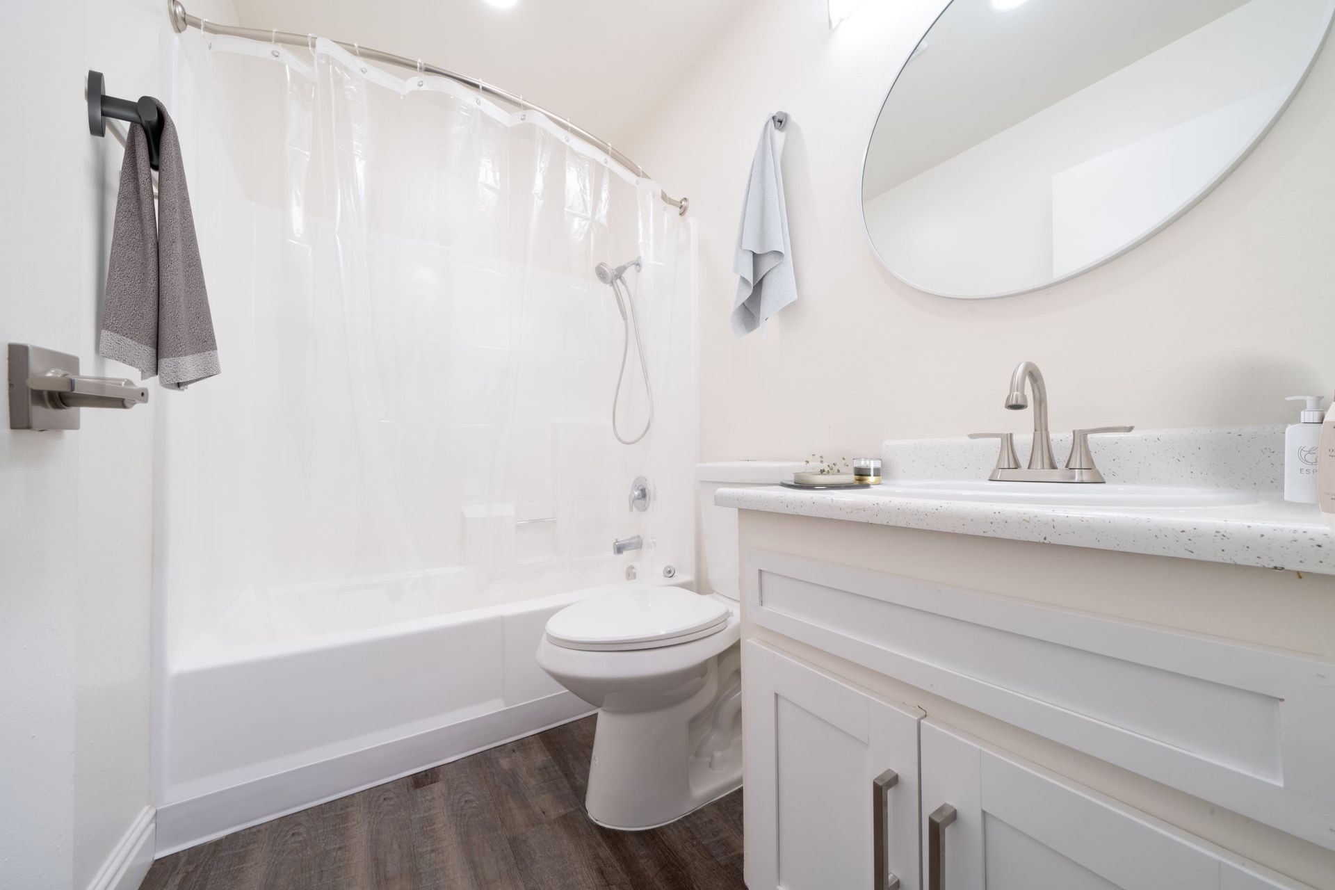 A bathroom with a toilet , sink , shower and mirror.