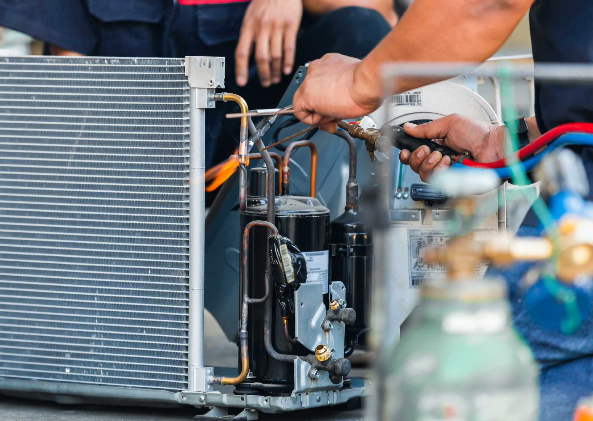 Mechanic working on an air conditioning unit, using tools.