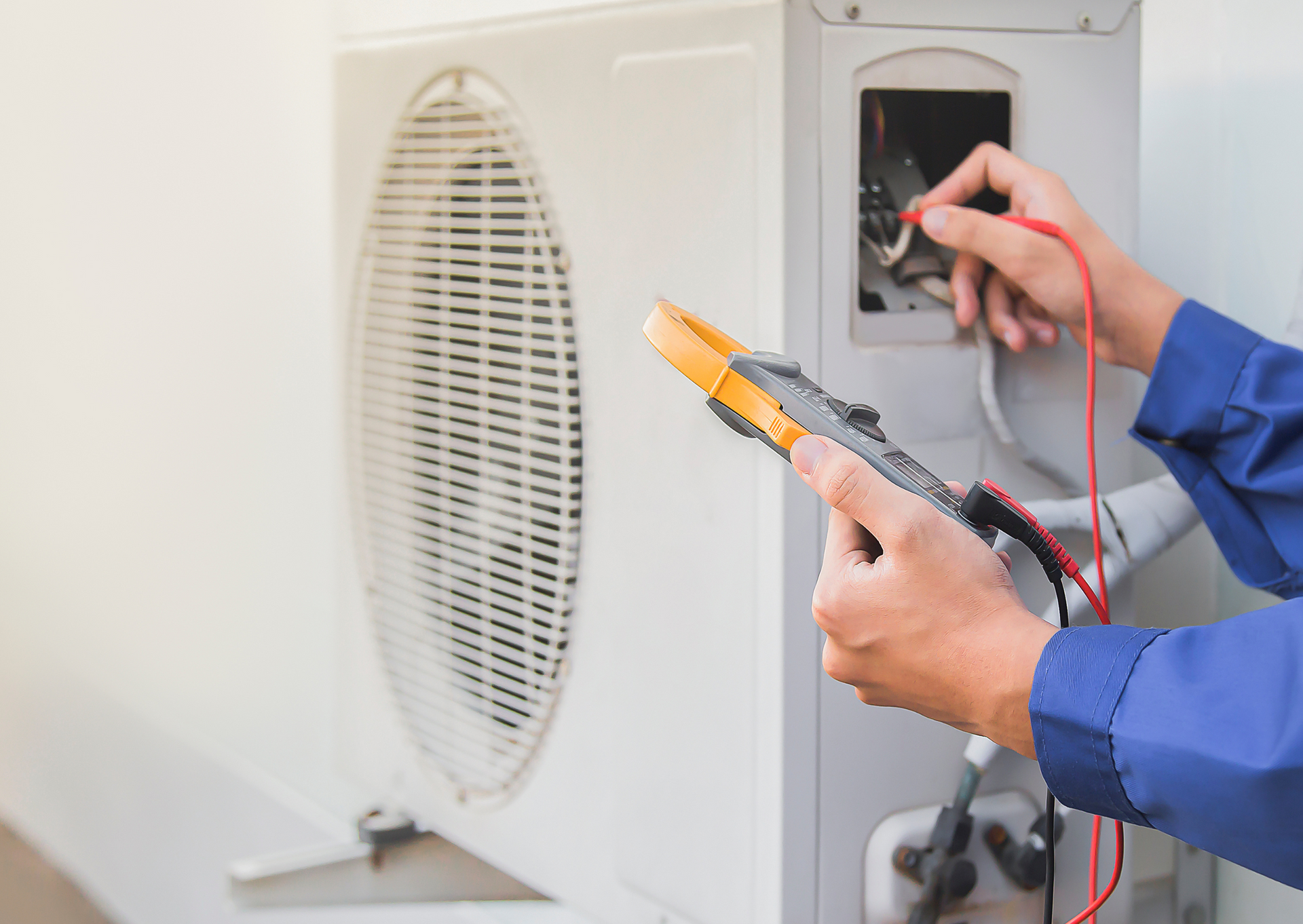 Technician tests an outdoor air conditioner unit with a multimeter.