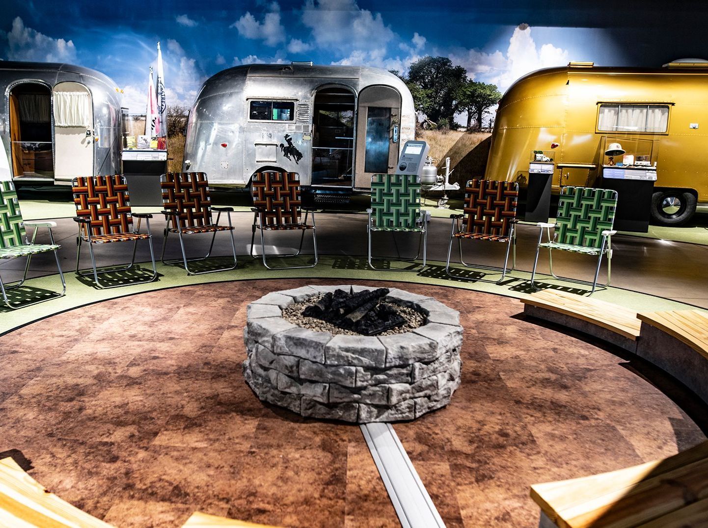 A museum gallery featuring simulated fireplace surrounded by chairs and Airstream Trailers