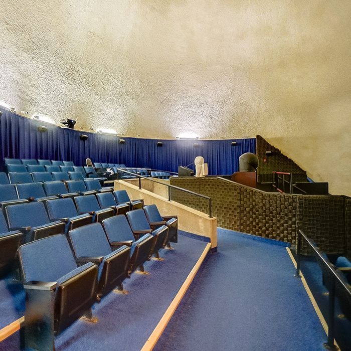 An empty auditorium with blue seats and blue curtains