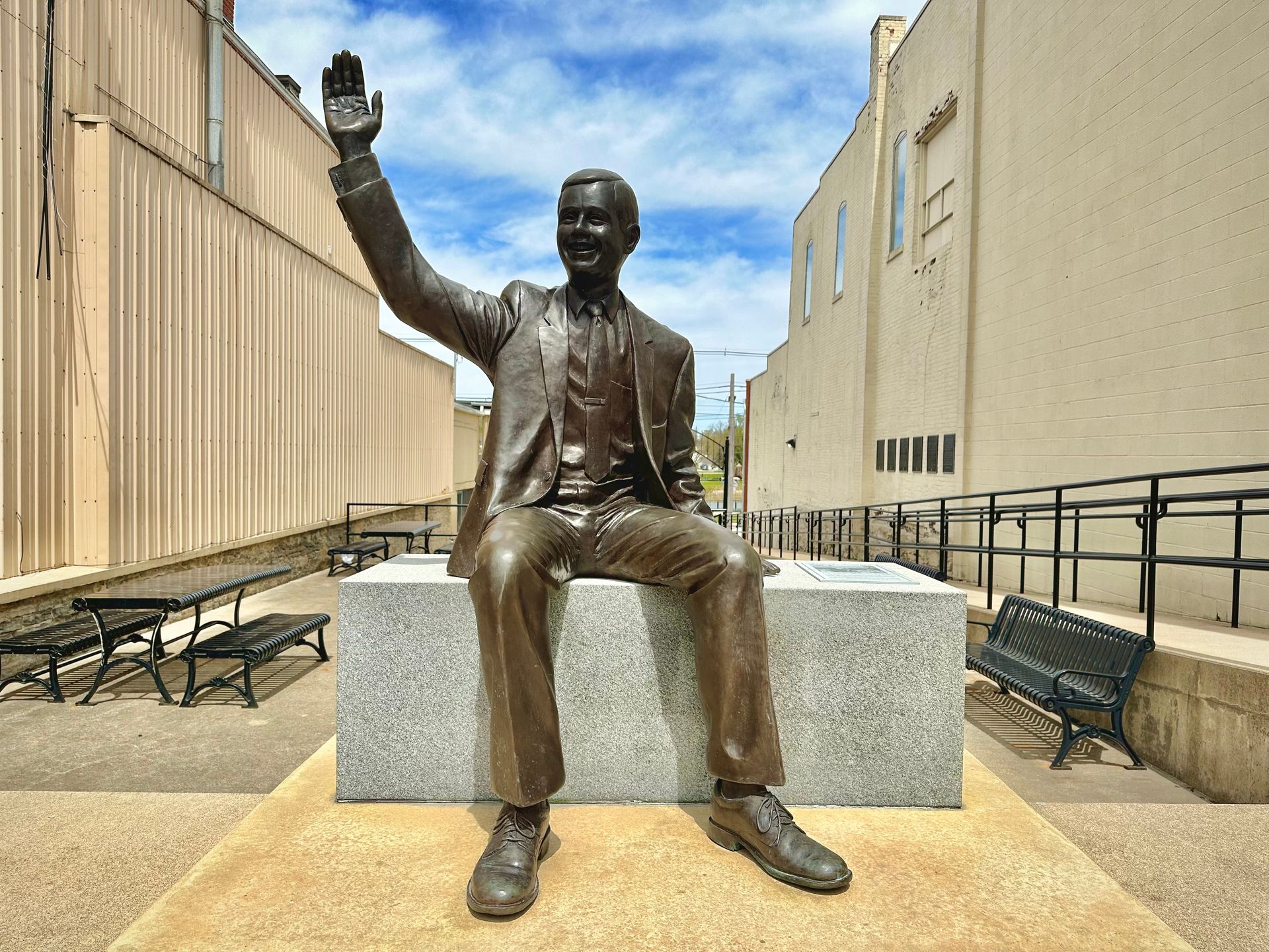 A life size bronze statue of Neil Armstrong waving.