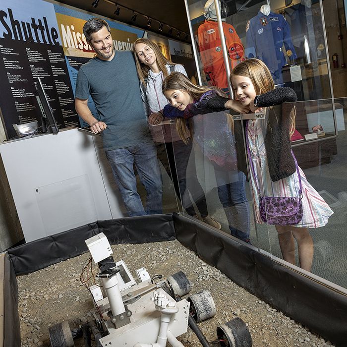A family is looking at a model of a rover in a museum.