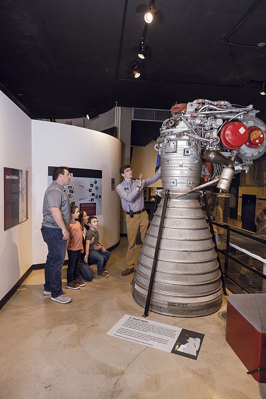 A group of people are looking at a large engine in the museum.