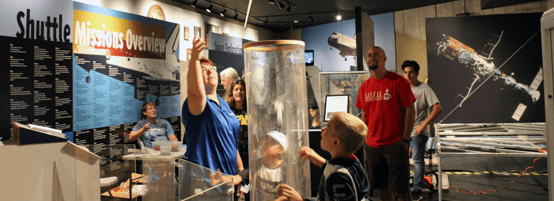 A group of people are standing in a museum looking at a display.