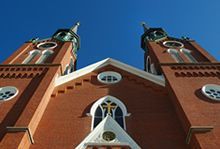 Looking up at St. Augustine Church in Minster -- replete with two towers against a blue sky.