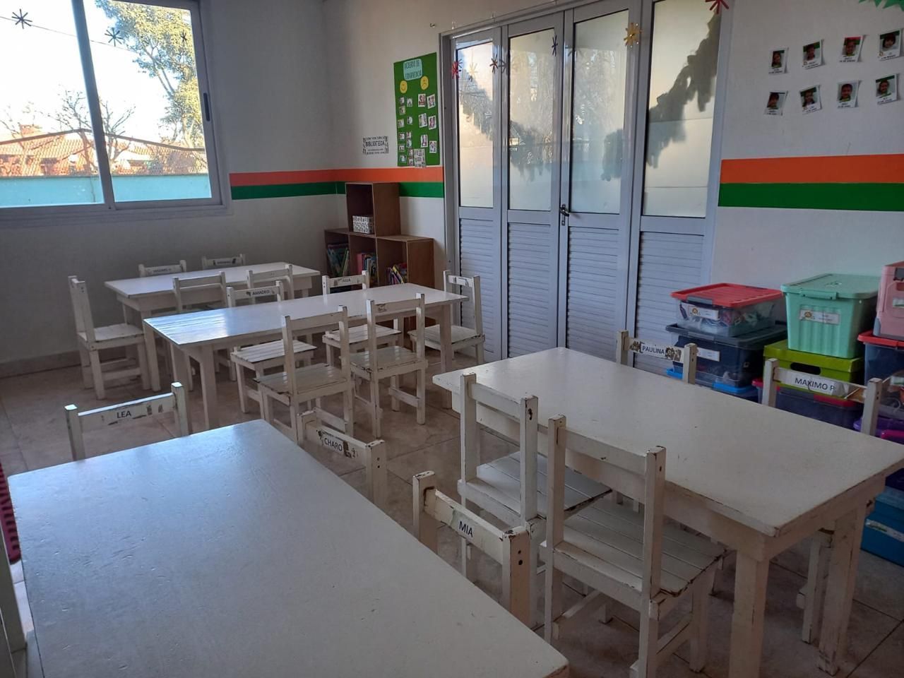 Un aula con mesas y sillas y una puerta.