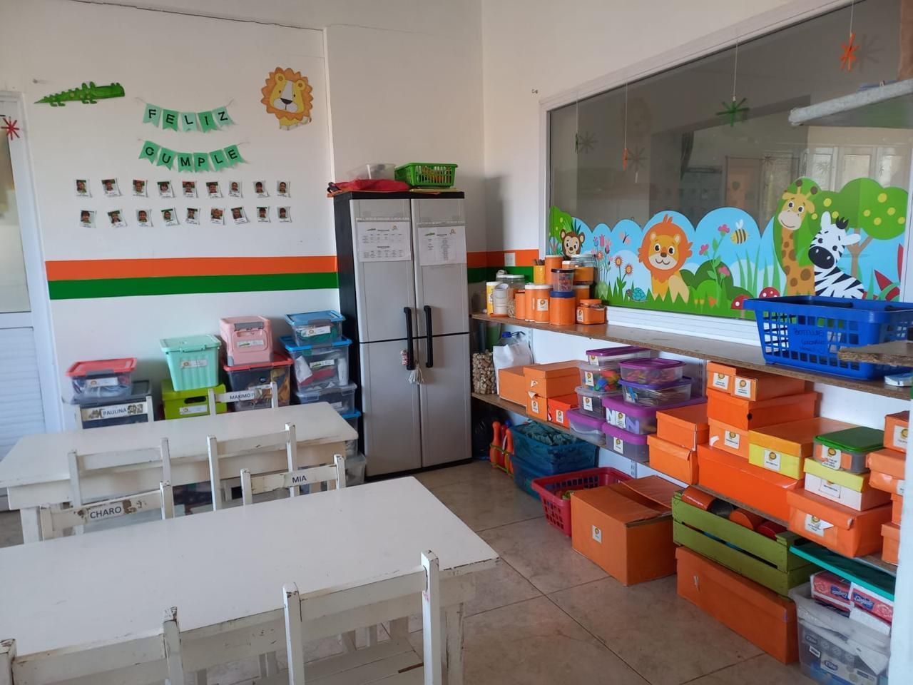 Un aula con mesas y sillas y un refrigerador.