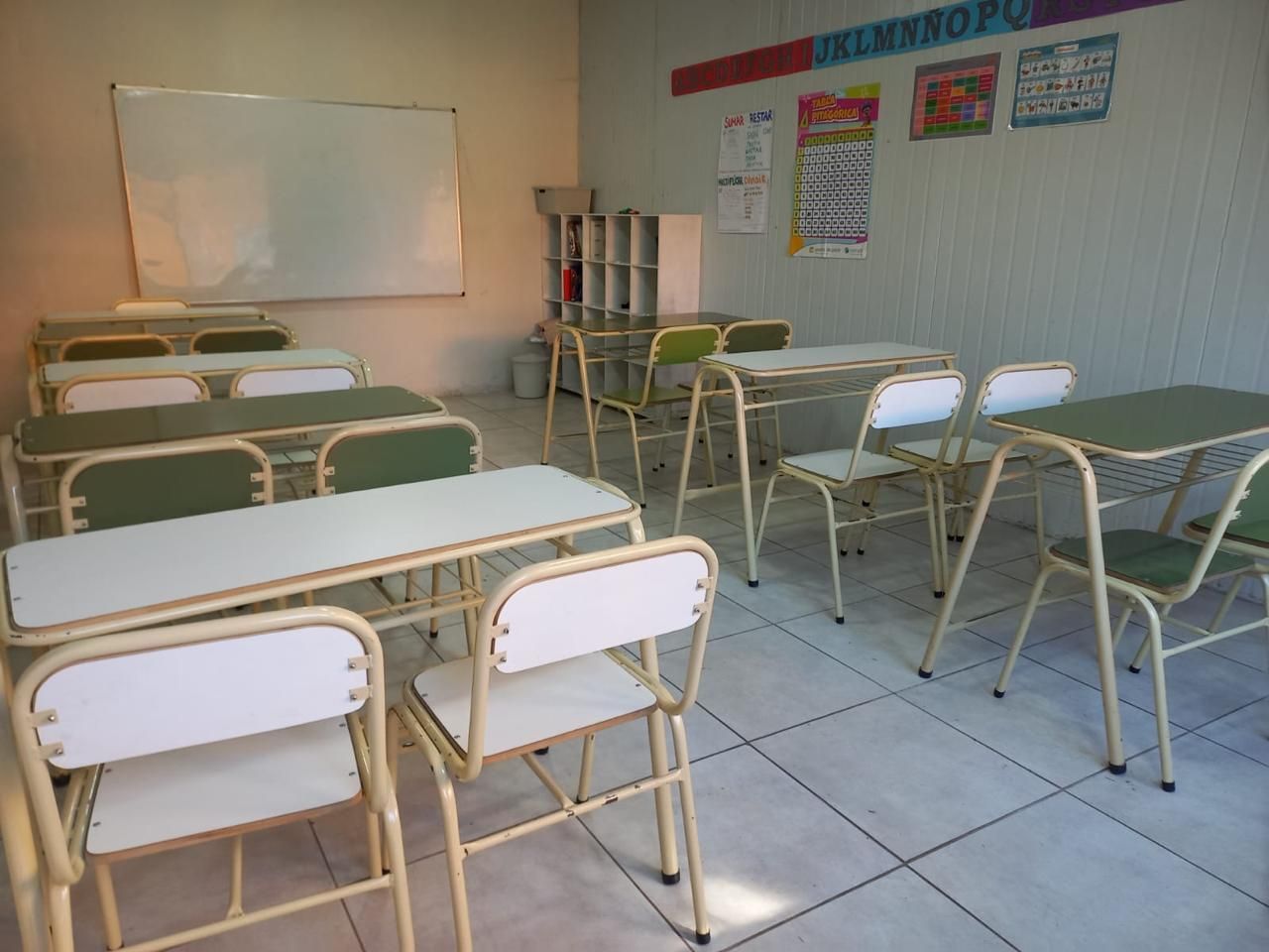 Un aula con muchos escritorios y sillas y una pizarra blanca que dice electrónica.