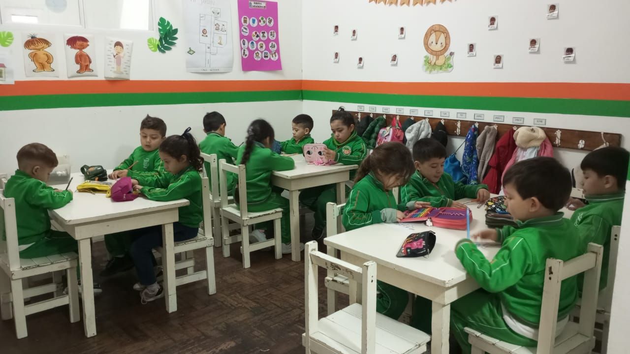 Un grupo de niños están sentados en mesas en un aula.