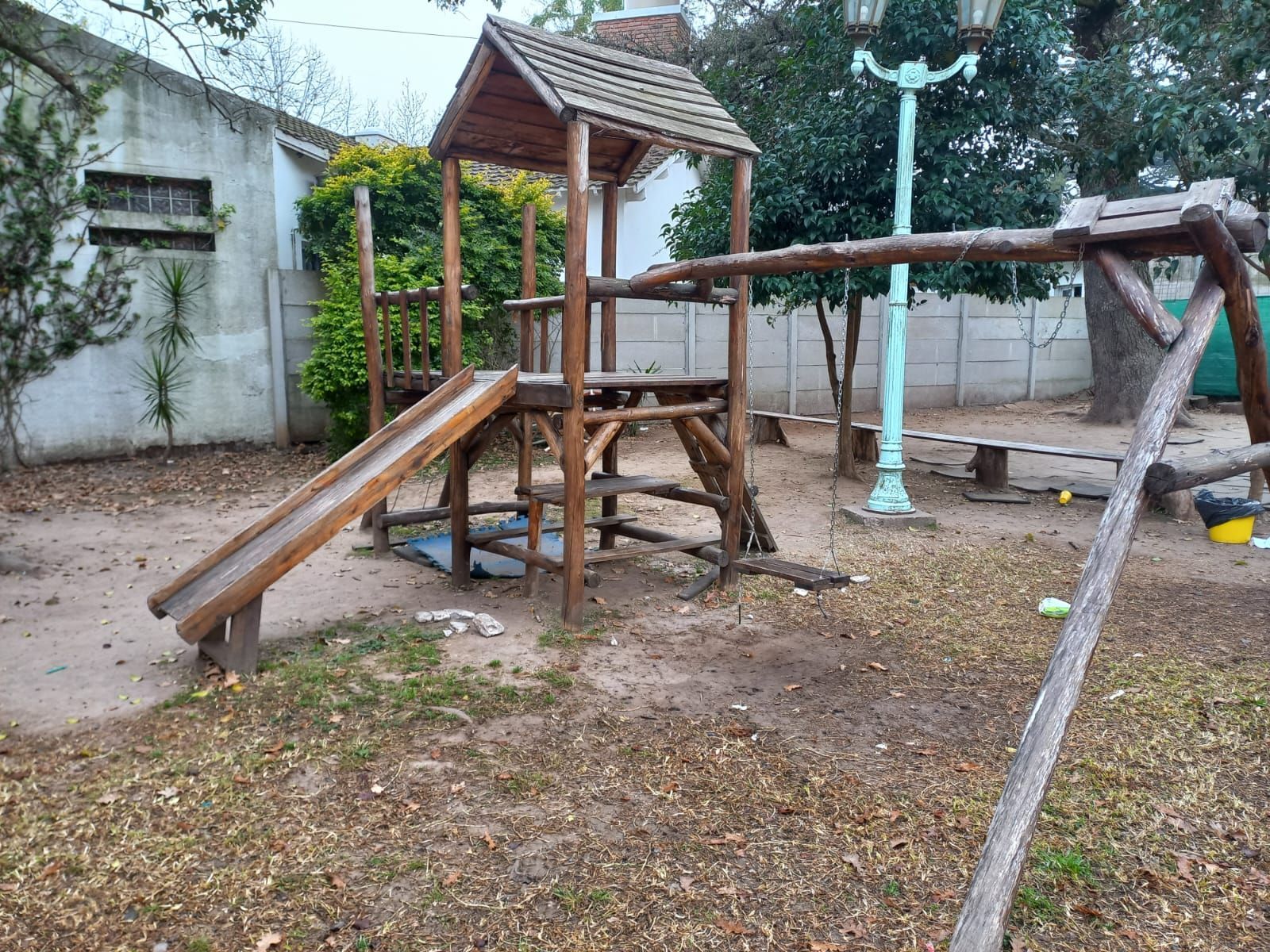 Un parque infantil de madera con tobogán y columpios en un parque.