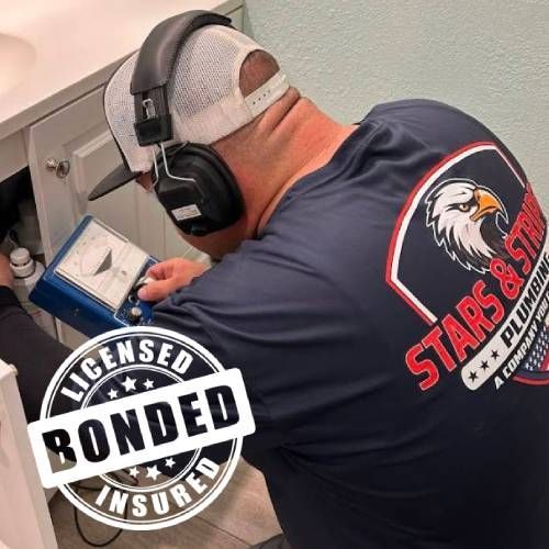 A man wearing headphones is working on a sink.