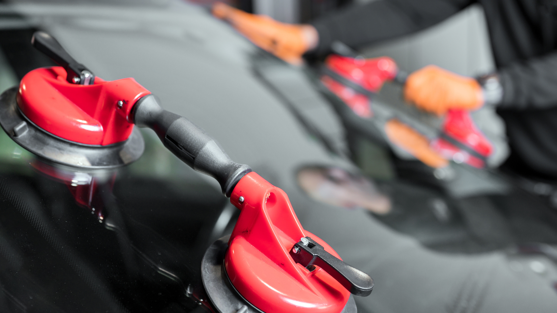 A close up of a person installing a windshield on a car.