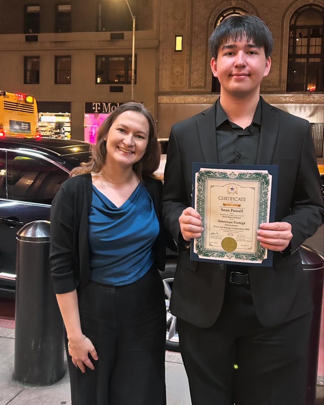 A woman is standing next to a man that is holding a certificate.