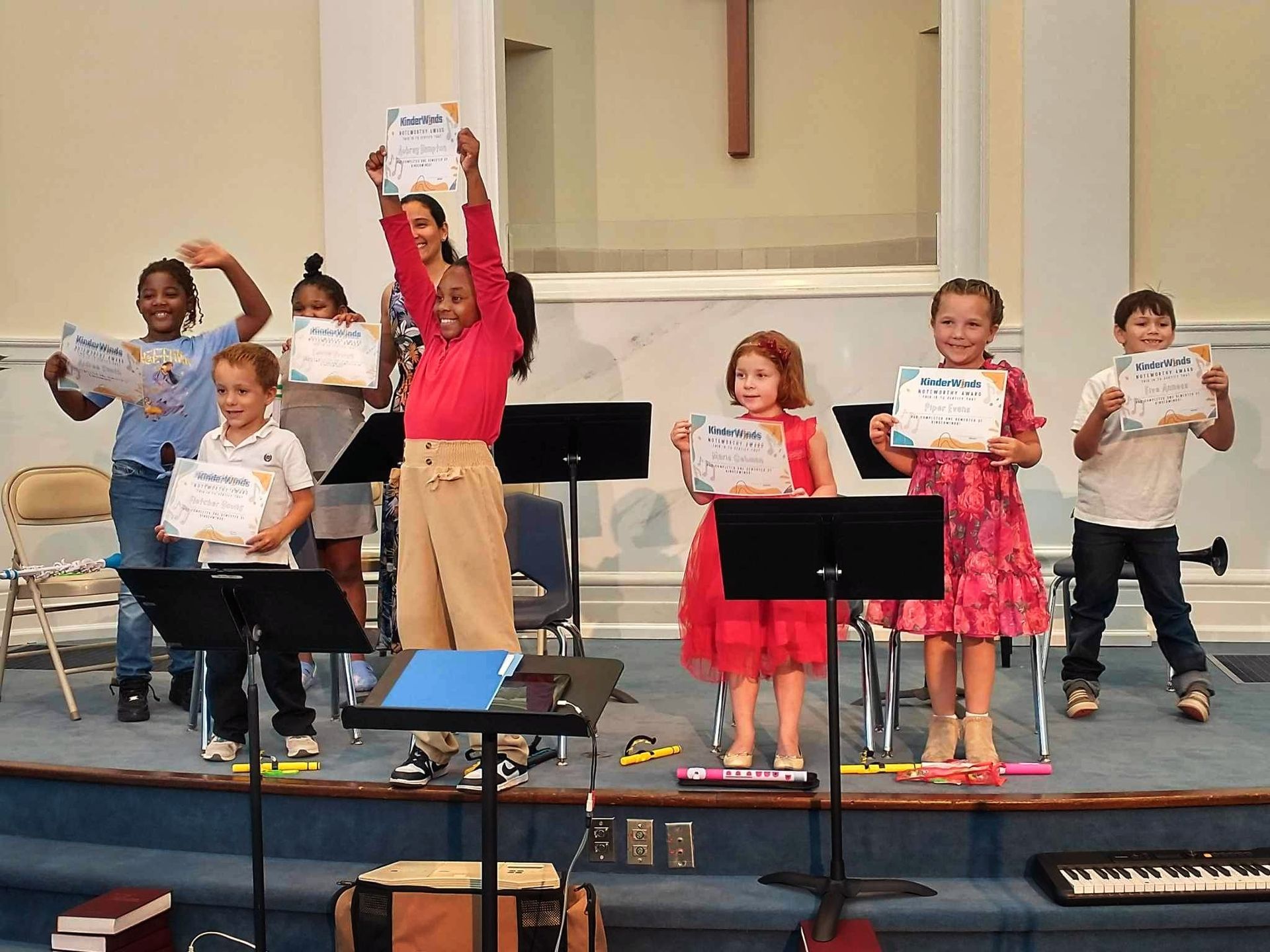A group of children are standing on a stage holding certificates.