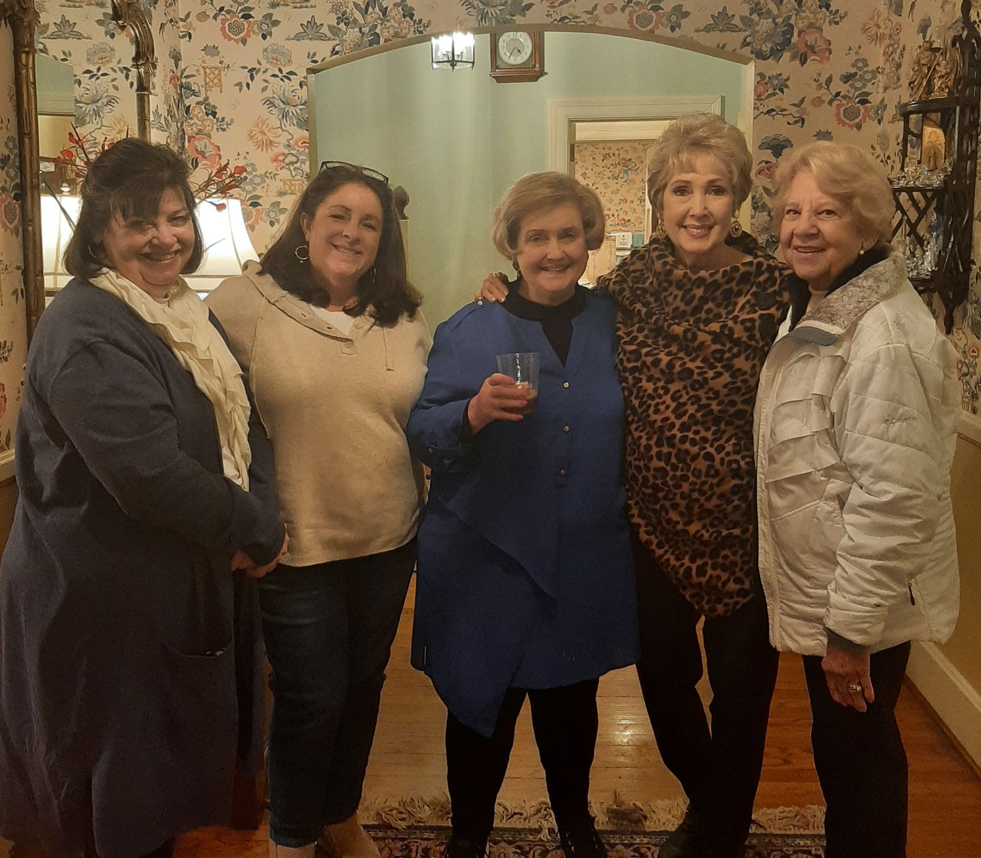 Five women stand next to each other in a warmly-lit room.