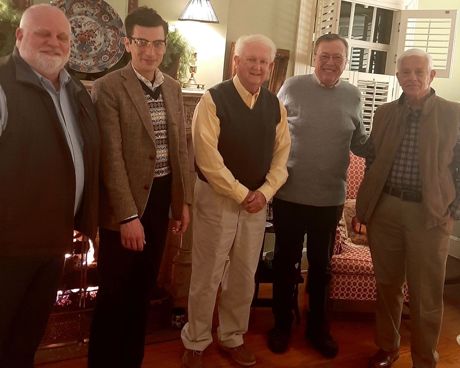 Five men stand next to each other in a warmly-lit room.