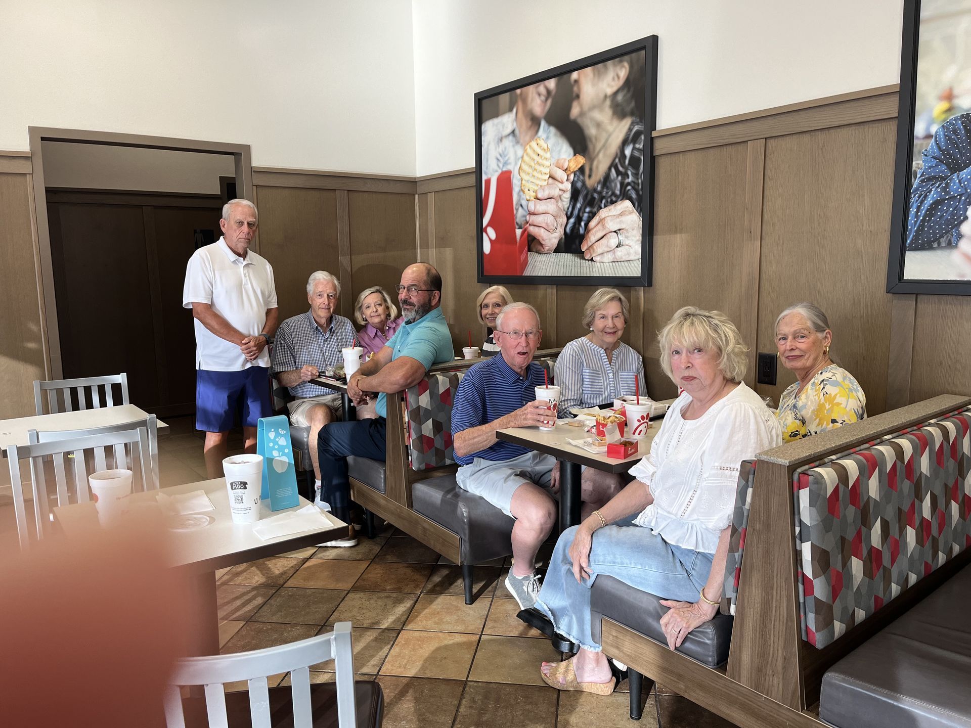 A group of older adults are sitting at tables in Chick-Fil-A.