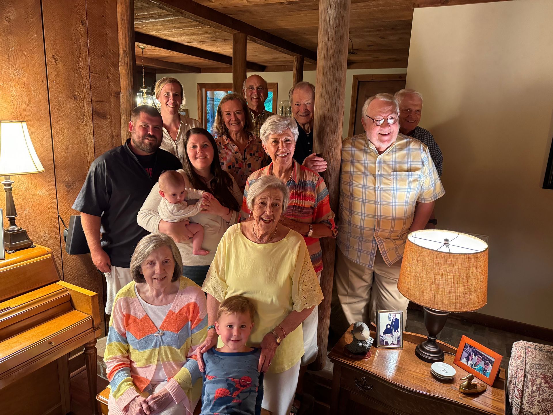 A small group poses together in a warmly lit room with wood-paneled walls and rustic decor.